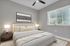 Inviting bedroom with plush bedding, modern decor, and ample natural light from a large window.