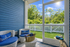 Charming screened porch with cozy wicker chairs and refreshing garden view under a sunny sky.