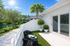 Charming patio with modern seating, lush greenery, and a serene water view under a bright blue sky.