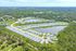 Vibrant aerial view of a modern residential neighborhood with pristine homes, scenic landscaping, and a serene lake backdrop.