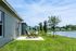 Charming lakeside view from a modern patio featuring cozy outdoor seating and lush green surroundings.