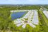 Aerial view of a serene residential community with modern homes surrounding a picturesque lake and lush greenery.