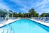 Inviting outdoor pool area with lush greenery, ample lounge seating, and clear blue skies, perfect for relaxation.