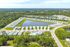 Aerial view of a serene residential community featuring modern homes surrounding a picturesque lake, with lush greenery and a sparkling pool.