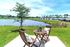 Inviting lakeside patio with cozy seating, perfect for enjoying serene water views and lush greenery.