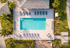 Luxurious aerial view of a sparkling blue pool surrounded by elegant lounge chairs and lush greenery, perfect for relaxation.