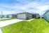 Charming suburban home with a well-maintained lawn, two-car garage, and inviting front porch under a bright blue sky.