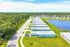Beautiful aerial view of a modern suburban community with neatly aligned homes adjacent to a tranquil lake, surrounded by lush greenery.