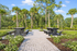 Inviting outdoor picnic area surrounded by lush greenery and palm trees, featuring elegant stone benches and a peaceful atmosphere.