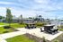 Bright outdoor communal area featuring picnic tables, a BBQ grill, and a modern playground, perfect for family gatherings and leisure activities.