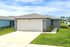 Charming one-story home with a modern facade, featuring a spacious two-car garage, well-maintained green lawn, and inviting pathway under a bright blue sky.