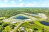 Aerial view of a picturesque housing community surrounded by lush greenery, featuring beautifully arranged homes and serene ponds.