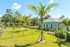 Inviting outdoor space featuring lush green lawns, manicured palm trees, and a charming residential building under a bright blue sky.