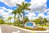 Welcome to Ravinia St. Lucie, an inviting entrance surrounded by lush palm trees and vibrant greenery under a picturesque blue sky.