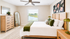Bright and spacious bedroom with elegant wood furnishings, large mirror, and picturesque window view of serene nature.