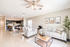 Elegant open-concept living room with a modern kitchen, featuring sleek gray furniture, stylish decor, and warm natural lighting.