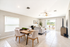 Bright open living space with modern dining area and cozy seating, featuring large windows and a serene outdoor view.