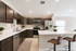 Modern kitchen with sleek dark wood cabinets, stainless steel appliances, and a spacious white countertop featuring elegant barstools.