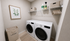 Modern and tidy laundry room featuring a sleek washer and dryer set, with decorative wall art and ample storage space.