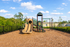 Inviting playground with slide and climbing structure, surrounded by lush greenery and clear blue skies, ideal for family enjoyment.