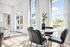 Bright contemporary dining area with elegant black chairs, a modern round table, and large windows offering scenic views and abundant natural light.