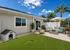 Charming backyard patio with cozy seating, lush greenery, and inviting atmosphere under a sunny blue sky.