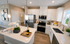 Modern kitchen with elegant white cabinets, sleek stainless steel appliances, and a stylish island featuring decorative orchids and a champagne display.