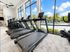 Modern gym with advanced treadmills and a scenic pool view through large windows, offering a vibrant workout environment.
