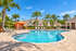 Luxurious poolside oasis with vibrant orange cabana, surrounded by palm trees and elegant lounge chairs, perfect for a tropical retreat.