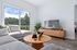 Bright living room with modern decor, featuring a stylish grey sectional, wooden coffee table, and a scenic view through large sliding doors.
