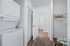 Modern laundry area featuring an efficient stacked washer and dryer, stylish wooden flooring, and convenient closet space.