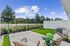 Charming outdoor patio with modern seating, lush greenery, and secure fencing, perfect for relaxation under clear blue skies.