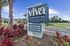 Vibrant Viva Communities sign at New Smyrna Beach, showcasing leasing options for one, two, and three-bedroom homes surrounded by lush landscaping.