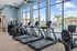 Bright and modern gym overlooking a scenic pool, equipped with state-of-the-art treadmills and exercise bikes for a premium fitness experience.