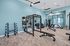 Modern fitness center with advanced weight training equipment and bright interior design featuring large windows and stylish flooring.