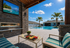 Luxurious outdoor patio with cozy seating, stone fireplace, and a sparkling pool, perfect for relaxation under sunny skies.