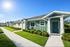 Charming apartment exterior with lush landscaping, modern siding, and inviting pathways under a clear blue sky.