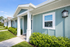 Charming exterior view of modern single-story apartments with vibrant blue siding and lush green landscaping.