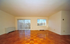 Bright and spacious living room with gleaming parquet flooring and large windows offering abundant natural light.