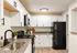 Modern kitchen with sleek black appliances, elegant white cabinetry, and stylish granite countertops.