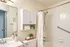 Elegant and modern bathroom featuring a pristine white bathtub with a shower, stylish vanity, and sleek cabinetry for storage.