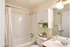 Bright and inviting bathroom with a classic white tiled bathtub, sleek fixtures, and elegant storage space.