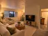 Inviting living room with elegant decor, featuring a large window view, cozy seating, and modern entertainment center, seamlessly connected to the dining area and kitchen.