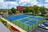 Vibrant community sports area featuring modern basketball and pickleball courts, surrounded by lush greenery and urban skyline.