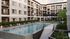 Luxurious outdoor pool at Leawood Village Apartments surrounded by comfortable lounge chairs and vibrant landscaping, with elegant apartment buildings in the background.