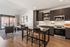 Open-concept apartment with dark cabinets, stainless steel appliances, island seating and a living area by a balcony door