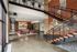 Two-story lobby with polished concrete floors, a floating steel staircase, a mosaic mural wall and the leasing desk