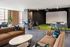 Lounge with velvet sofas, high-top tables and an indoor golf simulator with a projection screen and putting turf