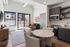 Open-concept apartment with a round dining table, kitchen with stainless appliances, living area and balcony door