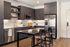 Apartment kitchen with dark cabinets, open shelving, a stainless steel refrigerator and a high-top island with woven stools